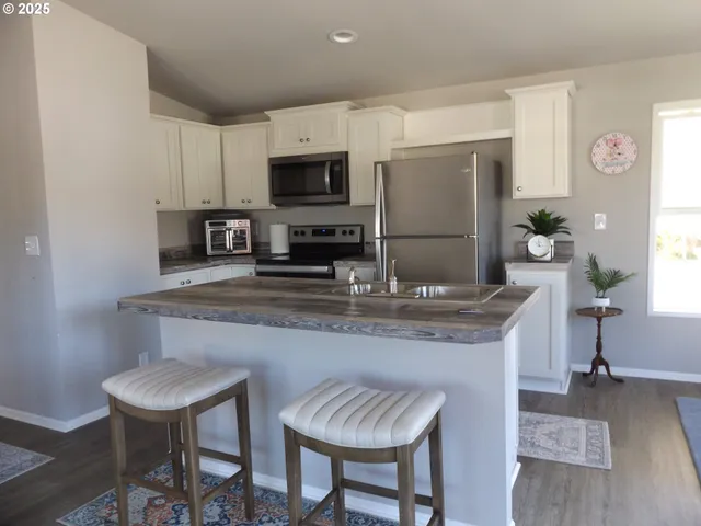 a kitchen with granite countertop a table chairs stove and microwave