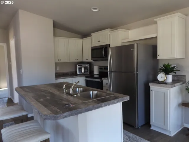 a kitchen with stainless steel appliances granite countertop a refrigerator a sink a stove a microwave and island