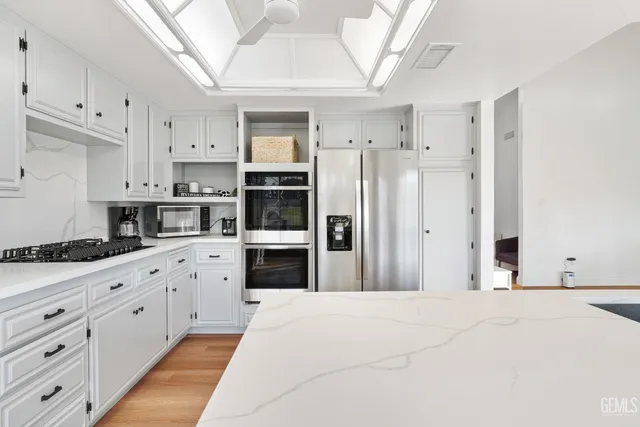 a kitchen with granite countertop a refrigerator oven a sink and cabinets