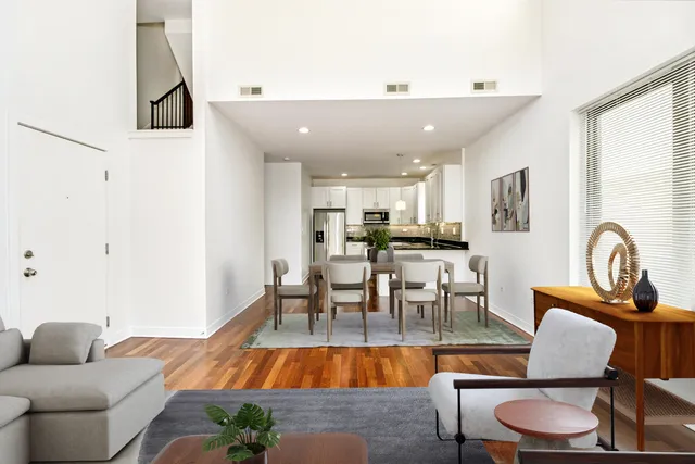 a living room with furniture and a dining table with wooden floor