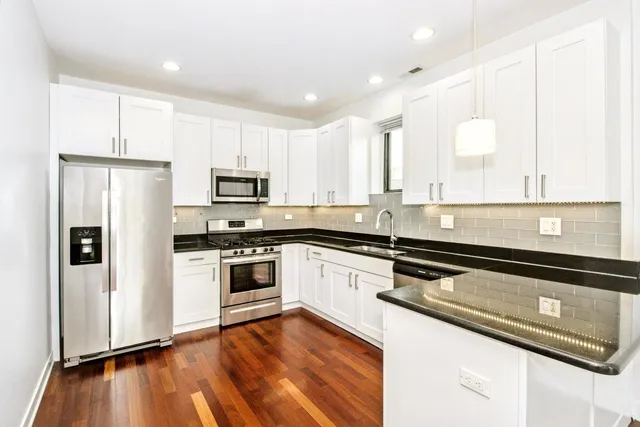 a kitchen with granite countertop white cabinets and stainless steel appliances