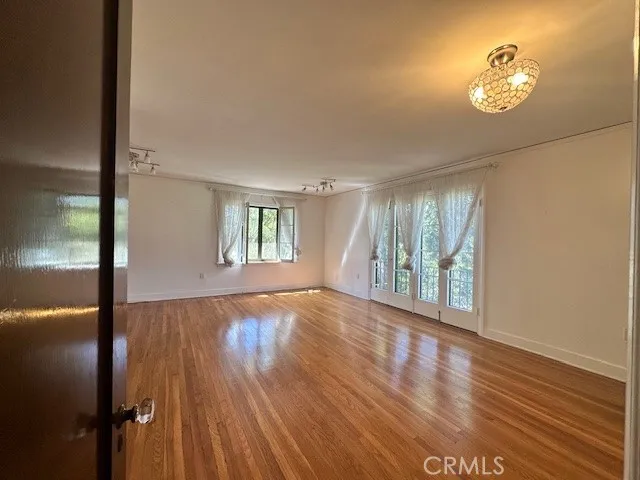 a view of an empty room with a window and wooden floor
