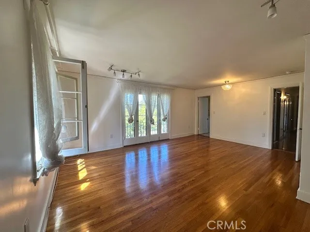a view of an empty room with wooden floor and a window