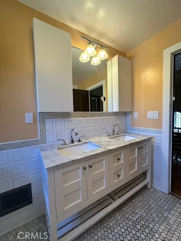 a bathroom with a granite countertop double vanity sink and mirror