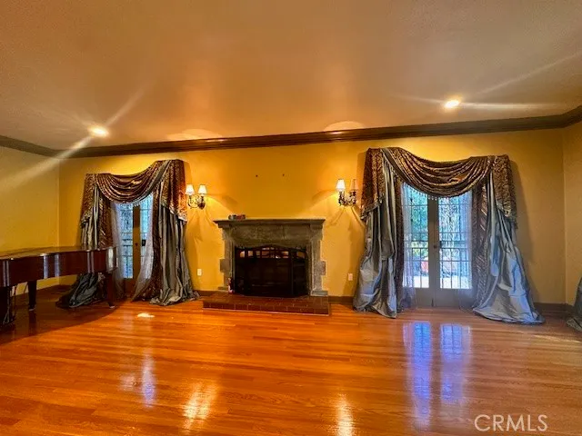 a view of an empty room with wooden floor and a fireplace