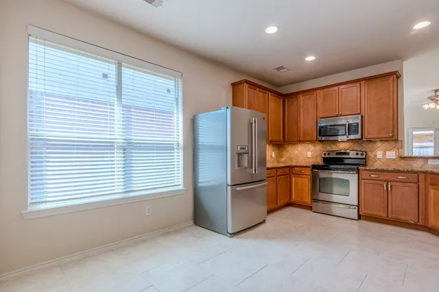 a kitchen with stainless steel appliances granite countertop a refrigerator a stove a sink and a microwave