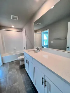 a bathroom with a granite countertop sink a toilet and mirror