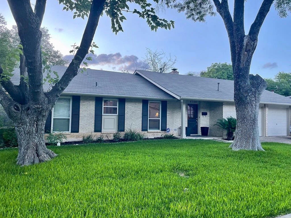 a front view of a house with a garden and trees