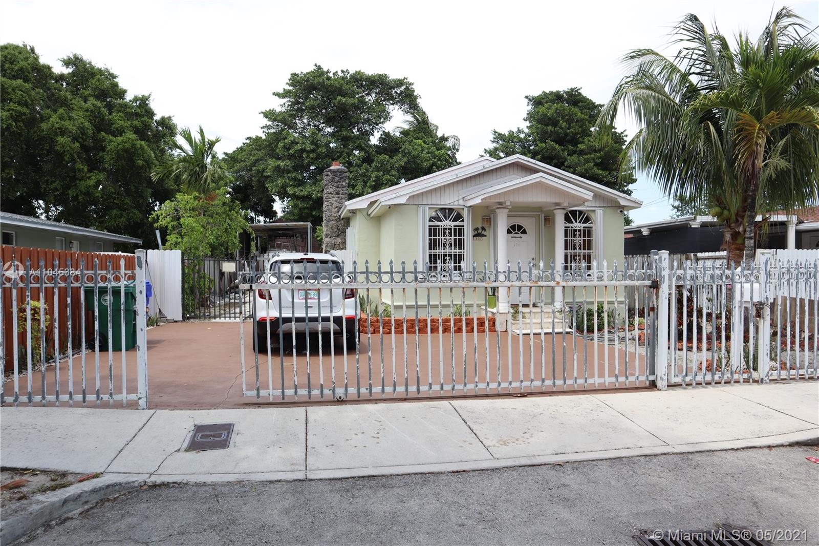 a view of a white house with a small yard and wooden fence
