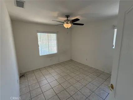 an empty room with windows and fan