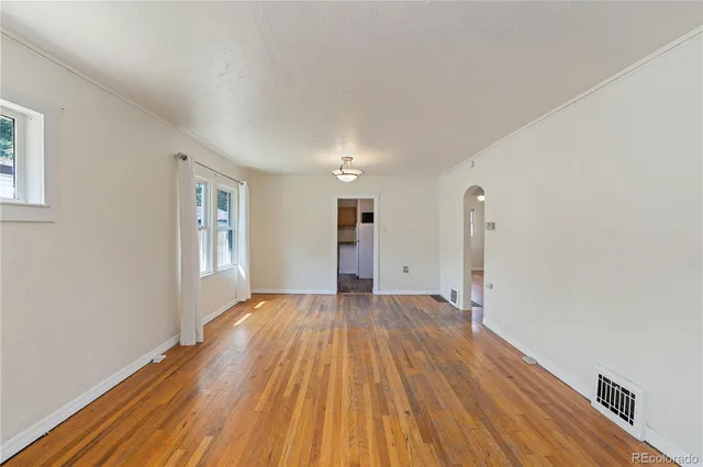 a view of empty room with wooden floor and window