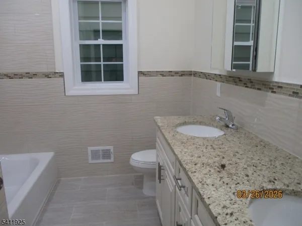 a bathroom with a granite countertop sink a toilet and a bathtub