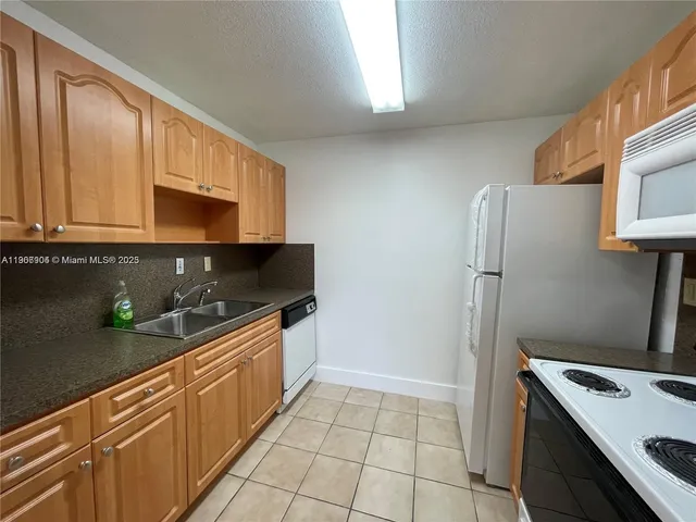 a kitchen with granite countertop a refrigerator and a sink