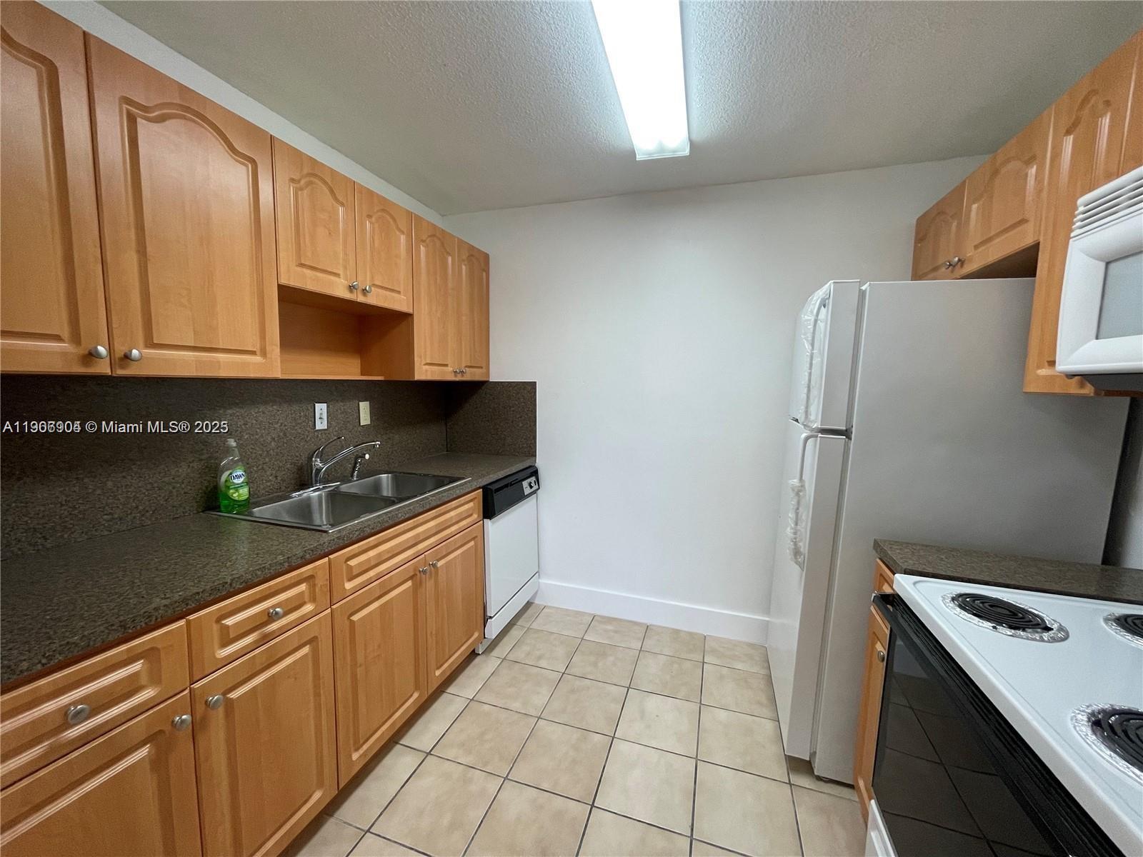 4670 West 13th Lane, Unit 504 Hialeah, FL 33012 - Photo 12 of 16 a kitchen with granite countertop a refrigerator and a sink
