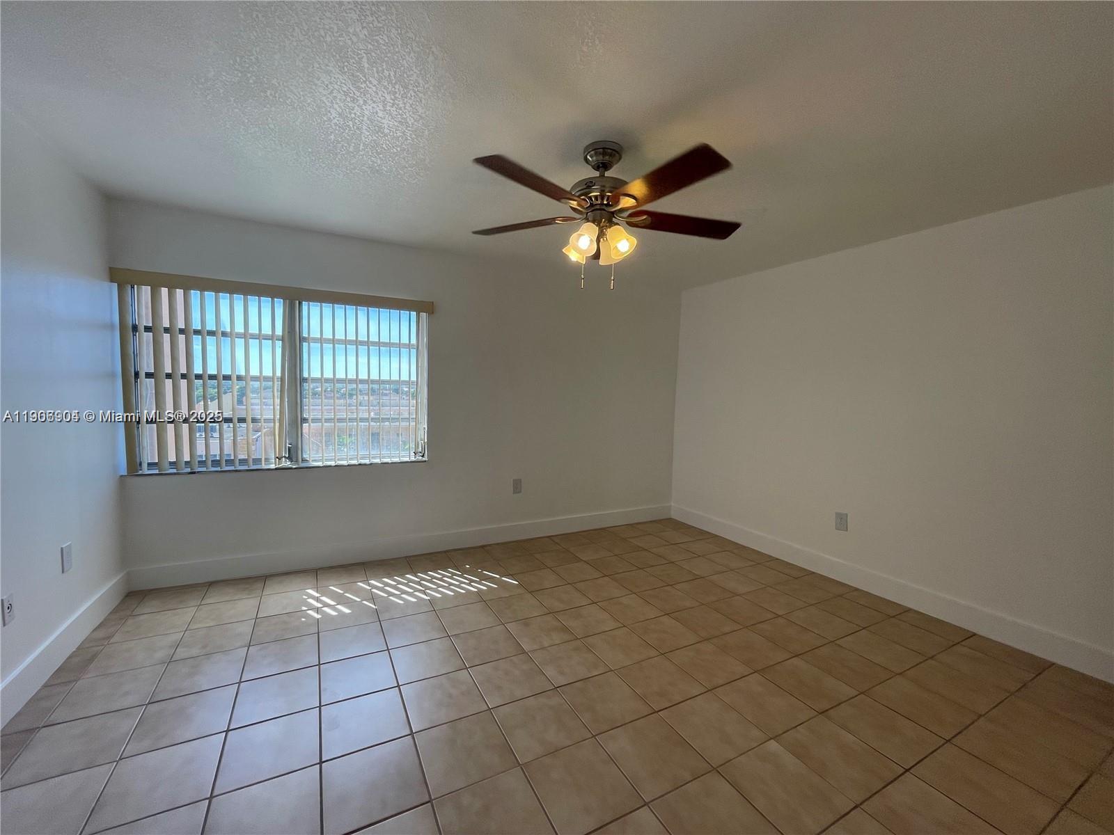 4670 West 13th Lane, Unit 504 Hialeah, FL 33012 - Photo 9 of 16 an empty room with windows and fan
