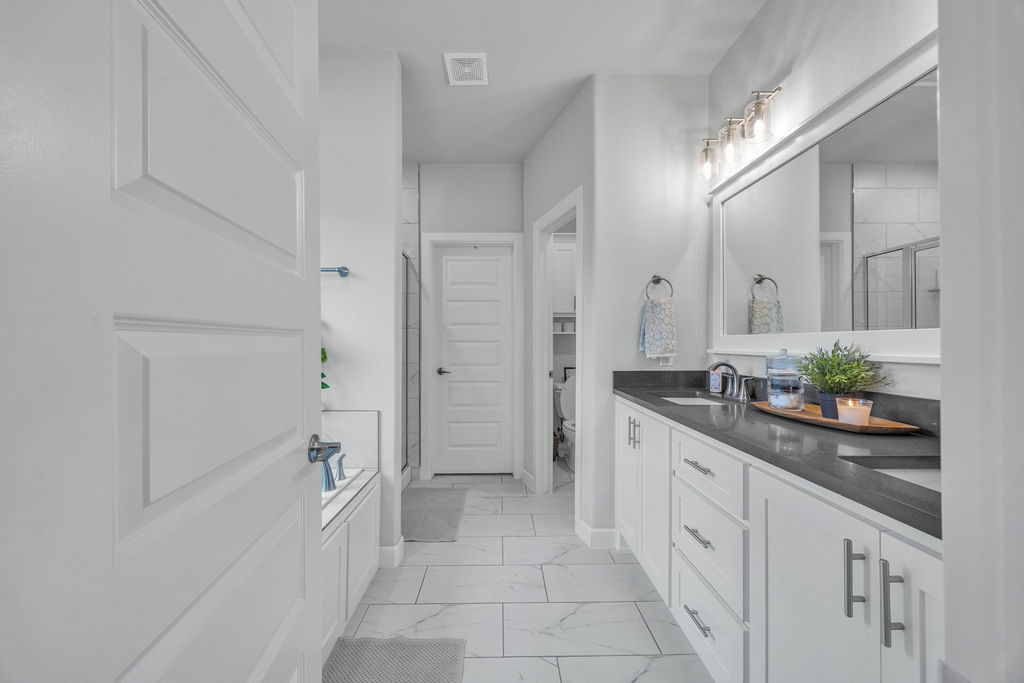 418 Casella Street Springdale, AR 72762 - Photo 17 of 34 Spacious bathroom featuring a dual vanity with a dark countertop, white cabinetry, and a large framed mirror