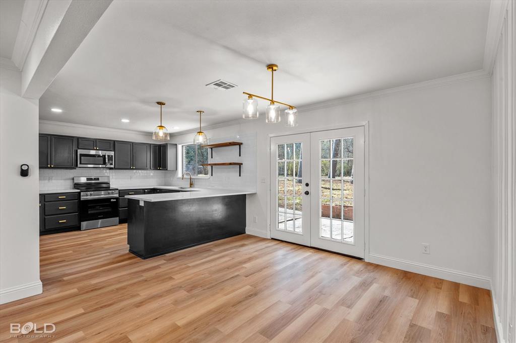 4136 Pines Road Shreveport, LA 71119 - Photo 12 of 38 Kitchen featuring crown molding, a peninsula, open shelves, light countertops, and french doors