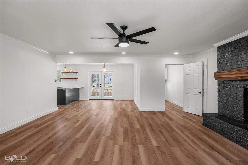 4136 Pines Road Shreveport, LA 71119 - Photo 18 of 38 Unfurnished living room with a ceiling fan, a brick fireplace, light wood-type flooring, ornamental molding, and recessed lighting