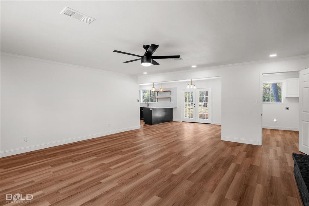4136 Pines Road Shreveport, LA 71119 - Photo 19 of 38 Unfurnished living room featuring a ceiling fan, light wood-type flooring, ornamental molding, hanging lights, and french doors
