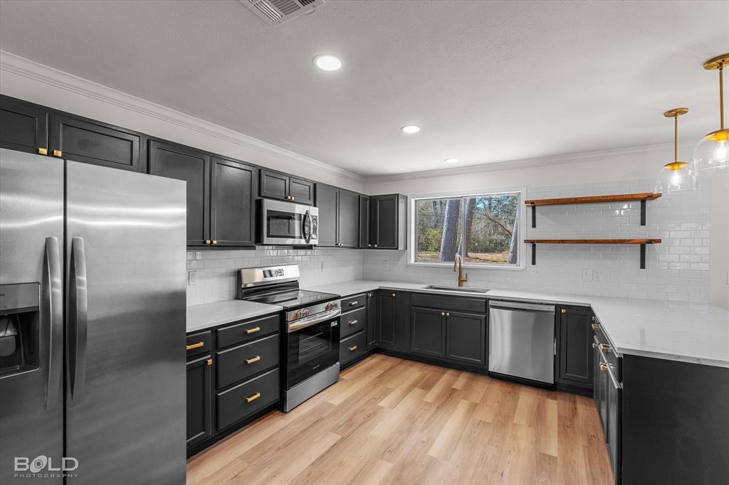 4136 Pines Road Shreveport, LA 71119 - Photo 9 of 38 Kitchen featuring stainless steel appliances, open shelves, pendant lighting, light wood-style flooring, and light stone counters