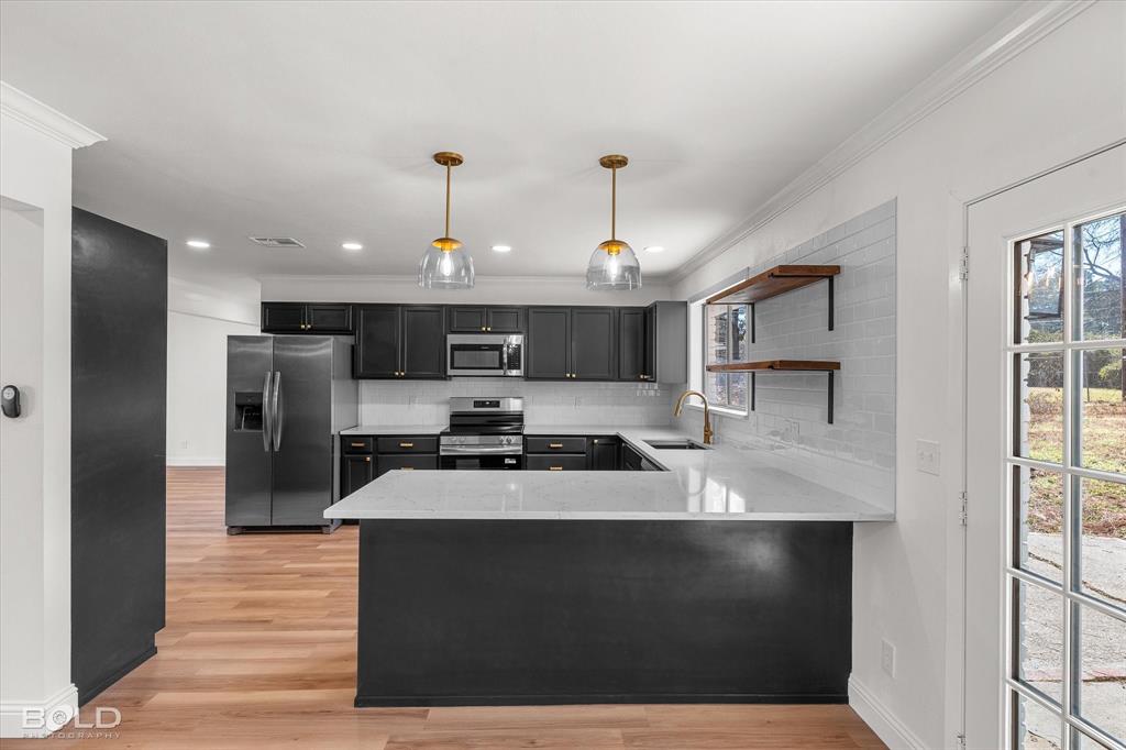 4136 Pines Road Shreveport, LA 71119 - Photo 10 of 38 Kitchen featuring open shelves, light stone counters, light wood-type flooring, backsplash, and ornamental molding