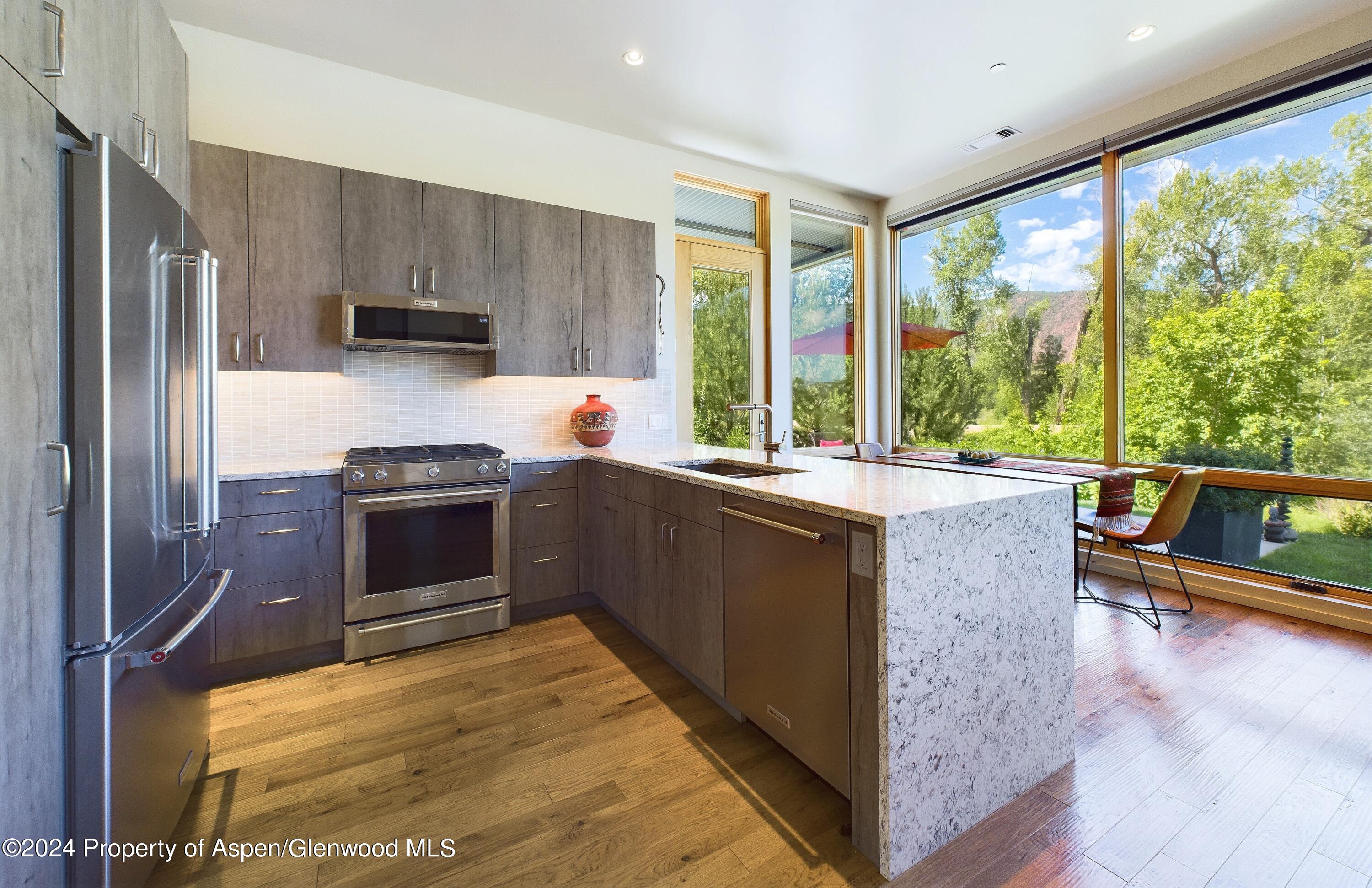 100 Evans Road, Unit 105 Basalt, CO 81621 - Photo 7 of 20 a kitchen with stainless steel appliances kitchen island granite countertop a refrigerator a sink dishwasher stove and oven