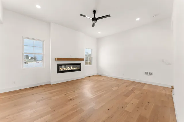 an empty room with ceiling fan and windows