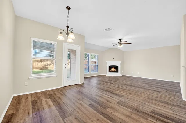 an empty room with wooden floor ceiling fan and windows