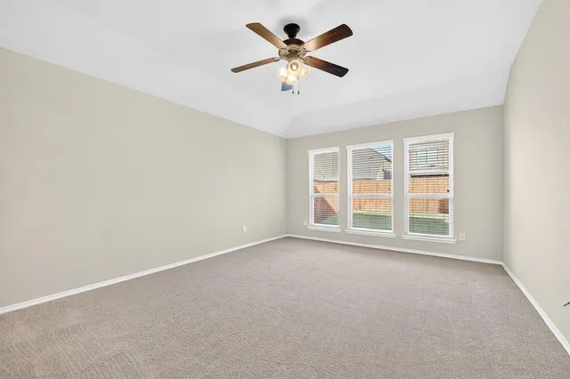 an empty room with chandelier fan and windows