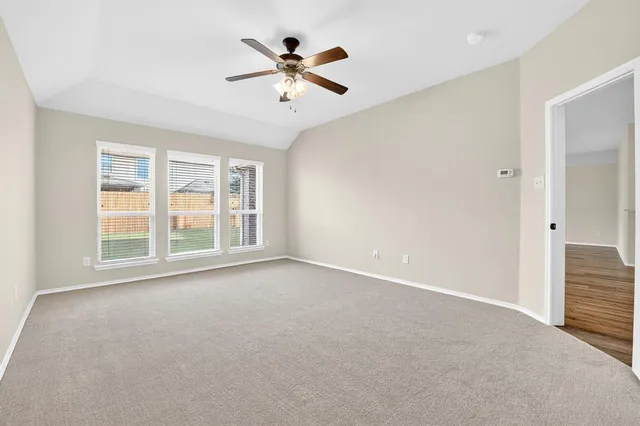 an empty room with windows and ceiling fan