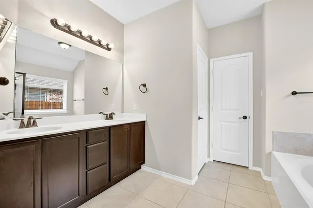 a spacious bathroom with a double vanity sink a mirror and a bathtub
