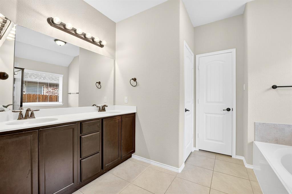 217 Rugby Lane McKinney, TX 75072 - Photo 31 of 40 a spacious bathroom with a double vanity sink a mirror and a bathtub