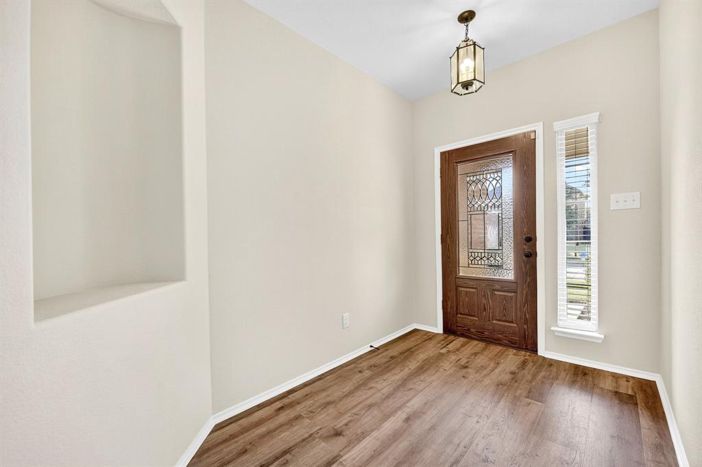 217 Rugby Lane McKinney, TX 75072 - Photo 6 of 40 an empty room with wooden floor chandelier and windows