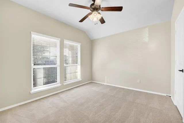 a view of an empty room with chandelier fan and a window