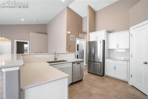 a kitchen that has a refrigerator a sink and white cabinets
