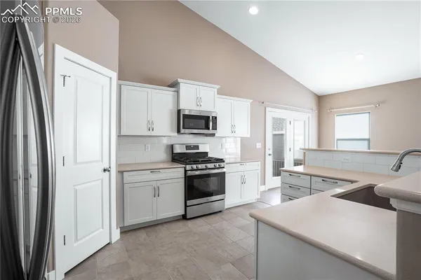 a kitchen with stainless steel appliances granite countertop a refrigerator and a stove top oven