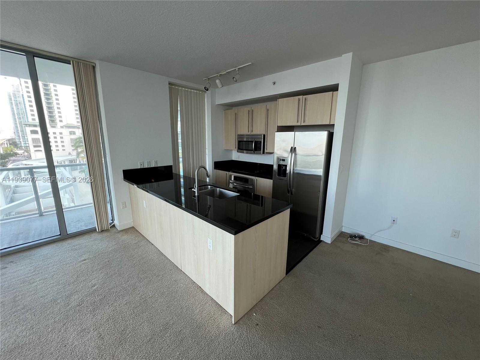 79 Southwest 12th Street, Unit 1112S Miami, FL 33130 - Photo 2 of 9 a kitchen with granite countertop a sink and a refrigerator