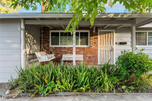 a view of a house with potted plants and a bench