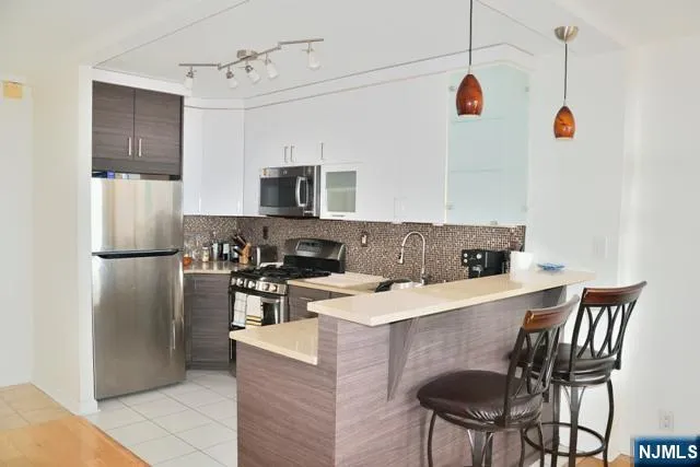 a kitchen with kitchen island a refrigerator a stove a microwave and chairs