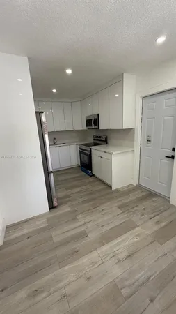 a kitchen with white cabinets and refrigerator