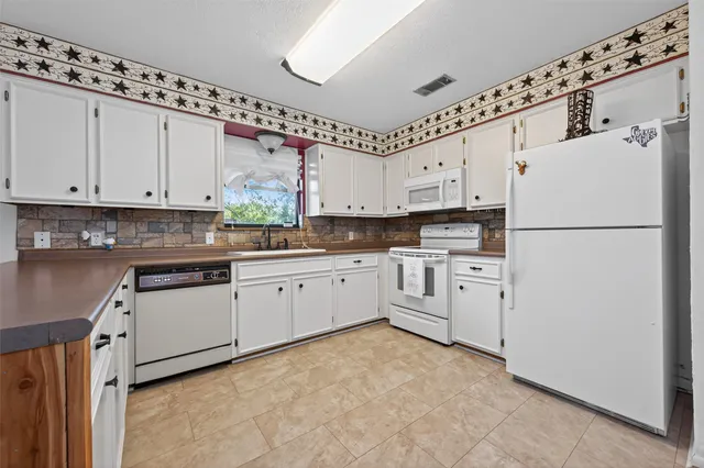 a kitchen with granite countertop white cabinets white stainless steel appliances and sink