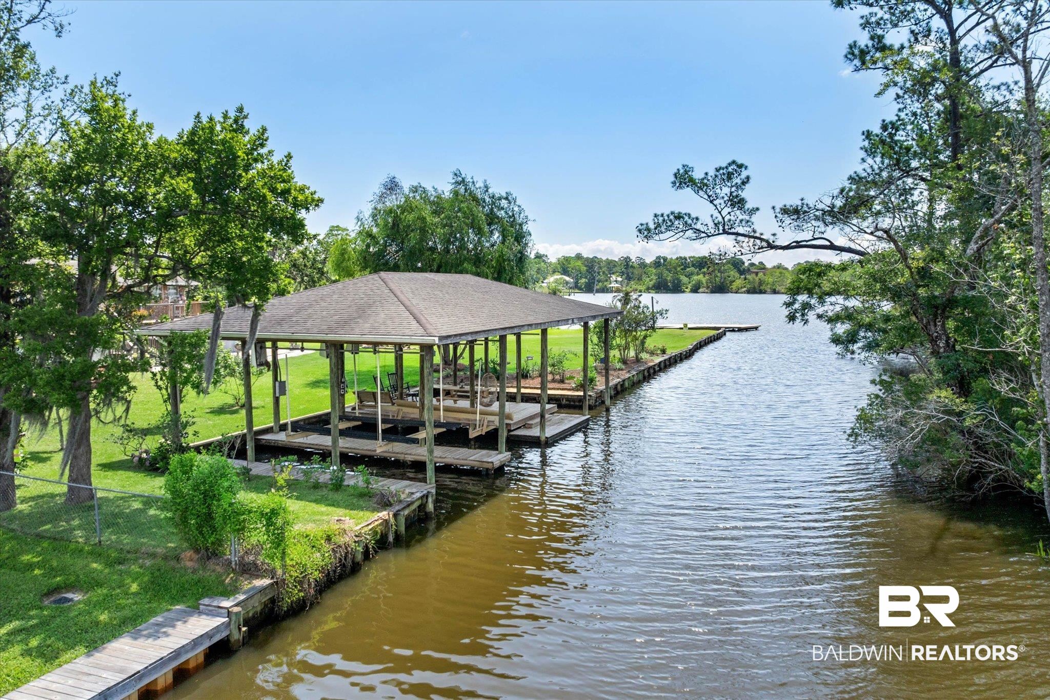 3801 Point Road Mobile, AL 36619 - Photo 3 of 55 Waterfront property featuring a covered boat dock with two boat slips, a separate wooden pier, and a grassy shoreline