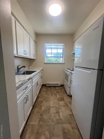 a kitchen with a refrigerator and white cabinets