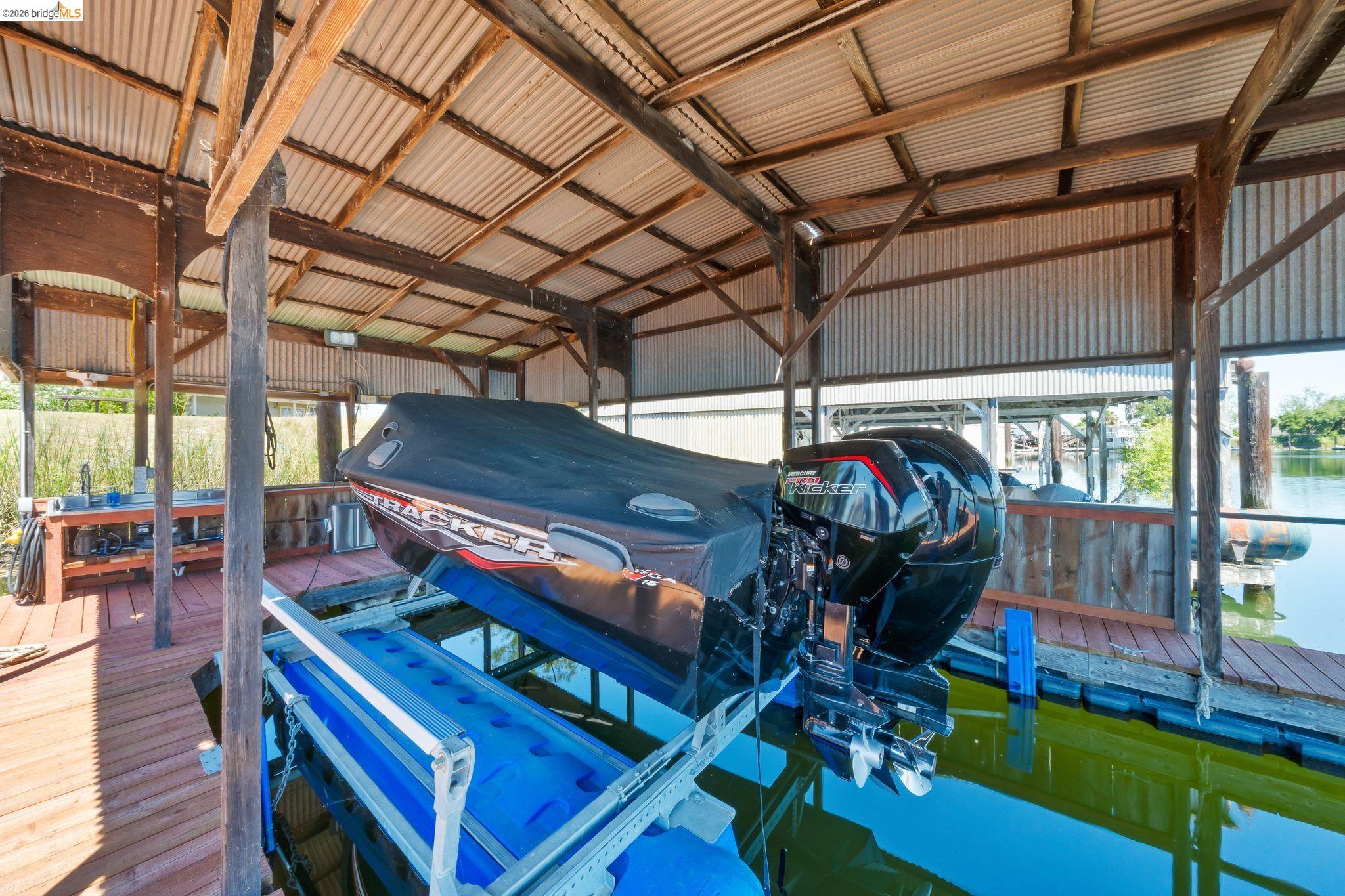 1704 Taylor Road Bethel Island, CA 94511 - Photo 58 of 73 Covered boat dock featuring a corrugated metal roof, wood support beams, and a boat lift