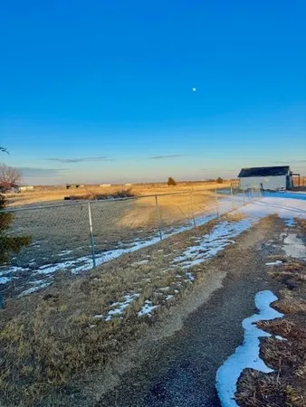 a view of a dry yard with wooden fence