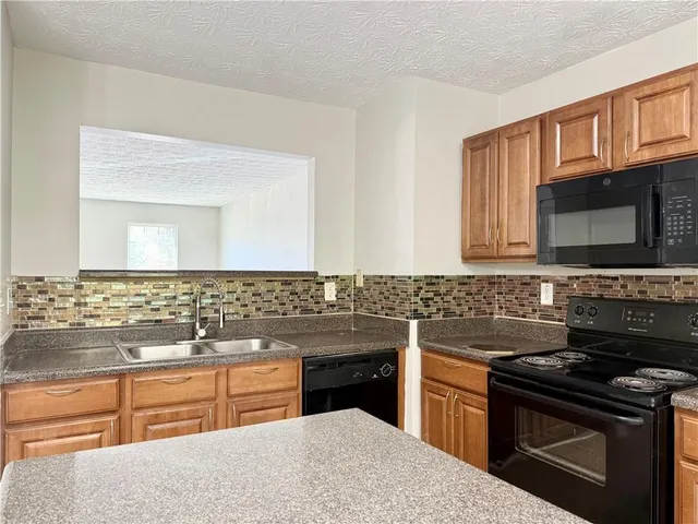 a kitchen with granite countertop a sink stove and microwave