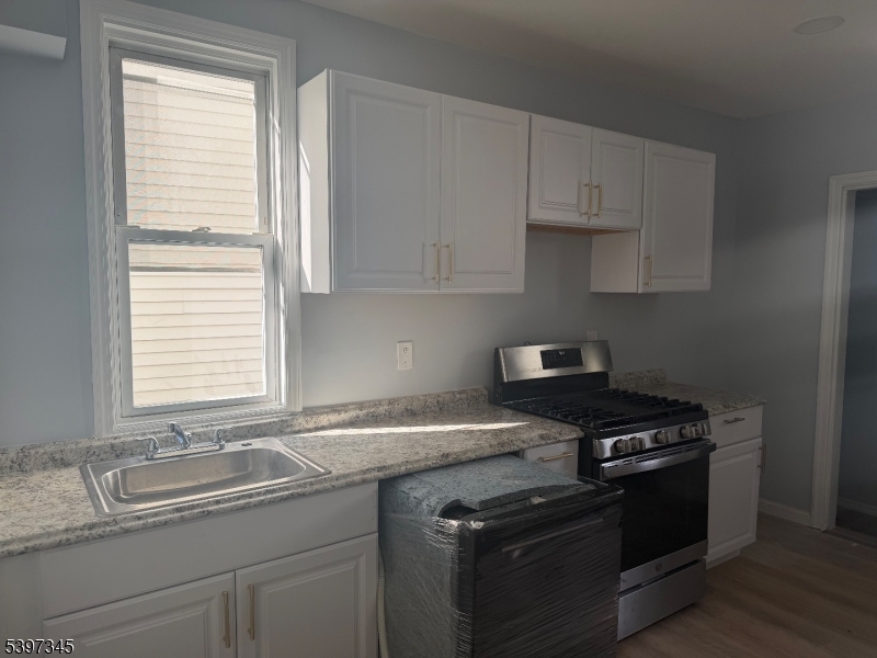 a kitchen with granite countertop a sink stove and cabinets