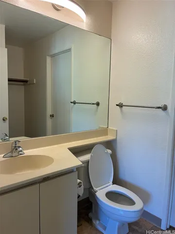 a bathroom with a granite countertop toilet sink and mirror