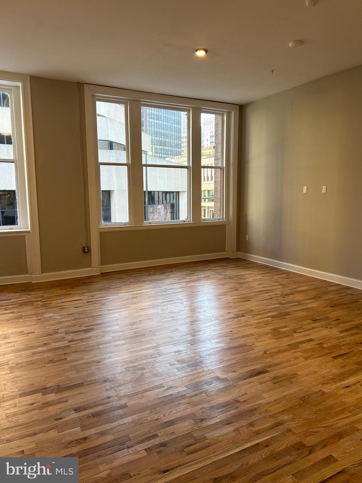 100 West Lexington Street, Unit 404 Baltimore, MD 21201 - Photo 4 of 27 an empty room with wooden floor and windows
