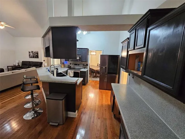 a living room with couches chairs and kitchen view with wooden floor